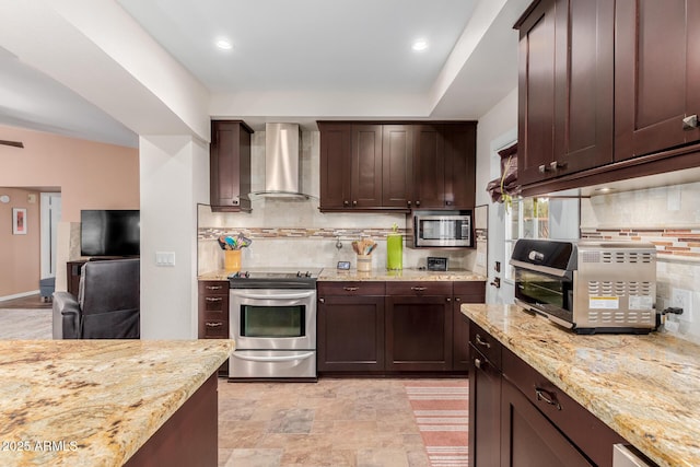 kitchen featuring appliances with stainless steel finishes, dark brown cabinetry, light stone countertops, decorative backsplash, and wall chimney exhaust hood