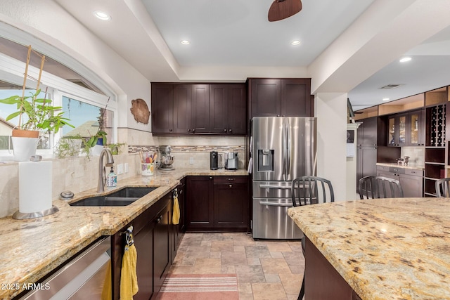 kitchen featuring stainless steel appliances, tasteful backsplash, sink, and light stone counters