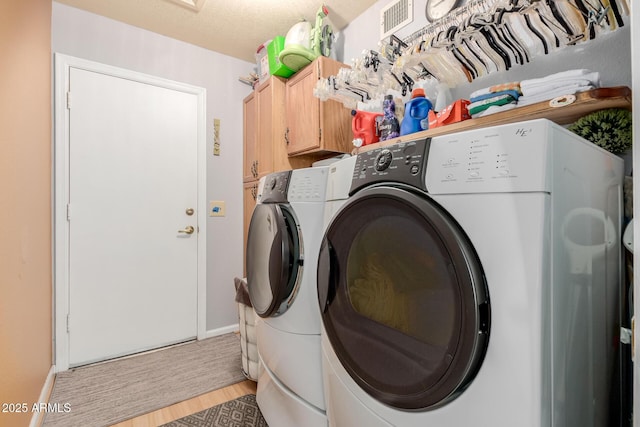 clothes washing area featuring cabinets, washer and clothes dryer, and light wood-type flooring