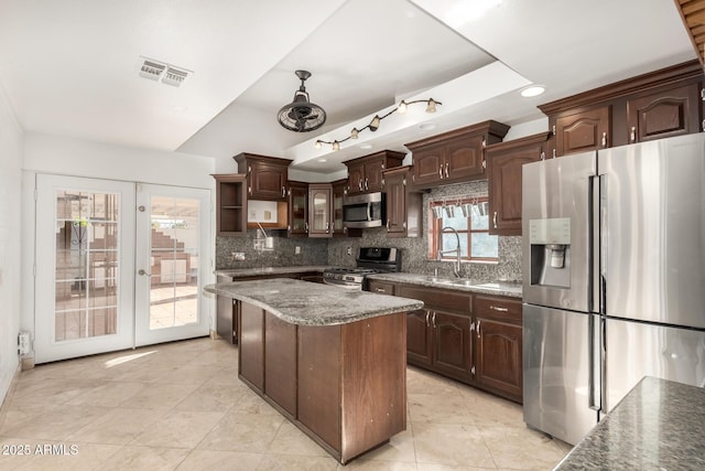 kitchen with appliances with stainless steel finishes, a center island, sink, and dark brown cabinets