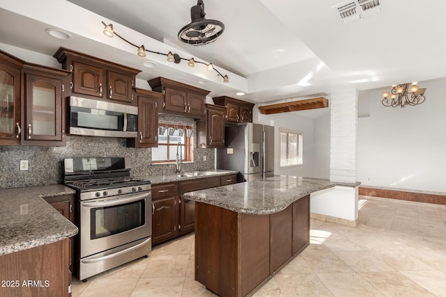 kitchen with a healthy amount of sunlight, dark brown cabinetry, appliances with stainless steel finishes, and a kitchen island