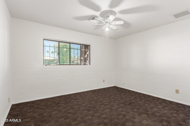 spare room featuring ceiling fan, brick wall, ornamental molding, and dark carpet