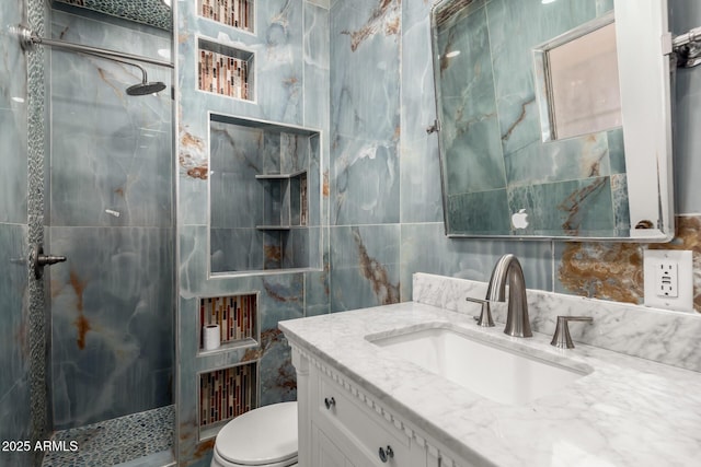 bathroom with tiled shower, vanity, toilet, and tile walls