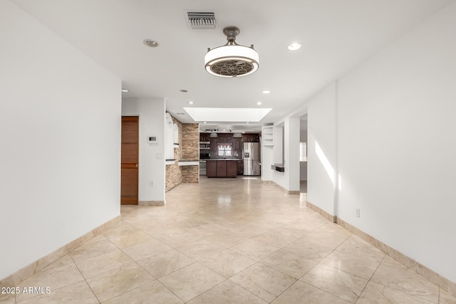 unfurnished living room with a skylight