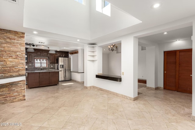 interior space with a towering ceiling, a chandelier, and sink