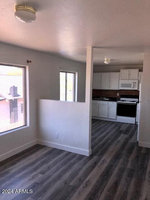 kitchen with white appliances, baseboards, dark countertops, dark wood-style flooring, and white cabinetry