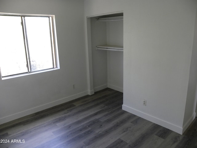 unfurnished bedroom featuring a closet and dark wood-type flooring