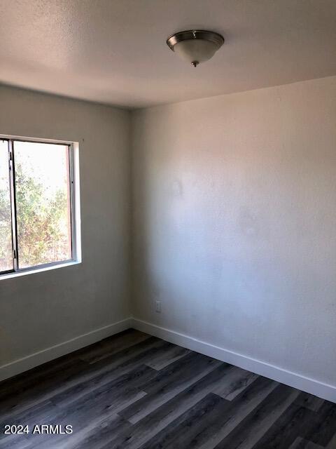 spare room featuring dark wood finished floors and baseboards