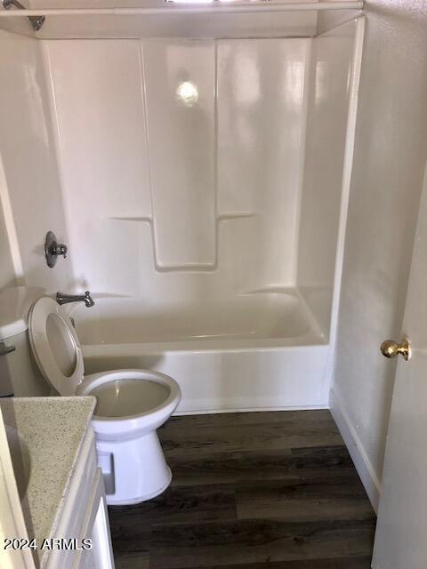 full bathroom with shower / bathing tub combination, vanity, hardwood / wood-style floors, and toilet