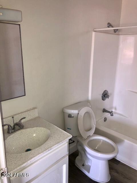 full bath featuring toilet, bathtub / shower combination, wood finished floors, and vanity