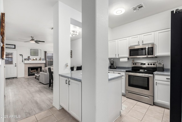1961 N Hartford St Unit 1092, Chandler, AZ 85225 - kitchen with stainless steel appliances, light tile patterned floors, white cabinets, a ceiling fan, and light countertops