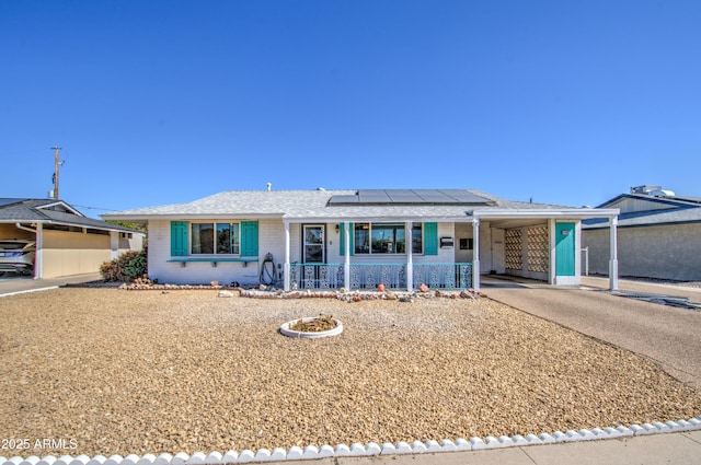 ranch-style home with solar panels, aphalt driveway, an attached carport, covered porch, and brick siding