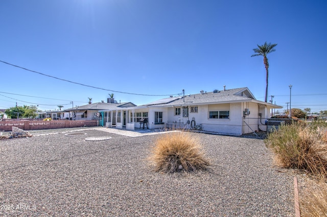 view of front of home with a patio, fence, and a sunroom