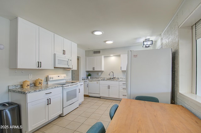 kitchen featuring white appliances, light tile patterned floors, visible vents, white cabinetry, and a sink