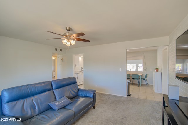 living room with light carpet, light tile patterned floors, visible vents, baseboards, and a ceiling fan