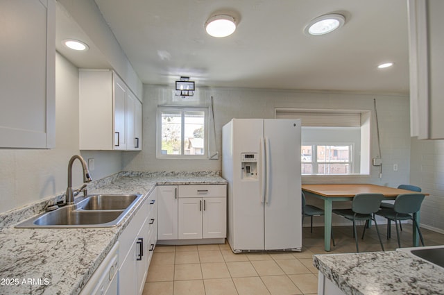 kitchen with light tile patterned floors, recessed lighting, a sink, white cabinets, and white fridge with ice dispenser