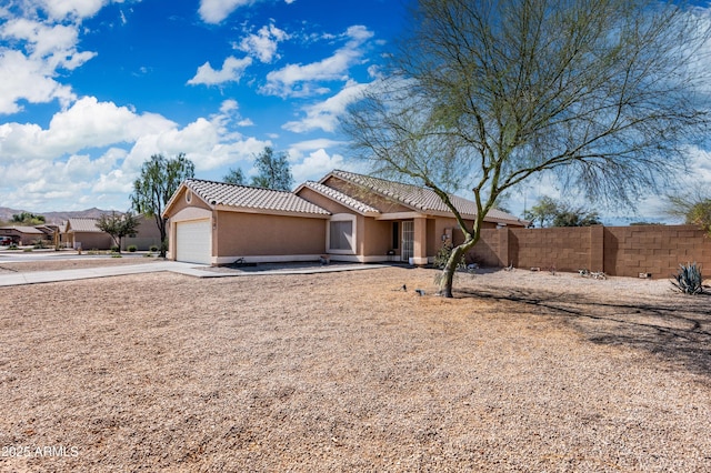 view of front of house with a tile roof, stucco siding, concrete driveway, an attached garage, and fence