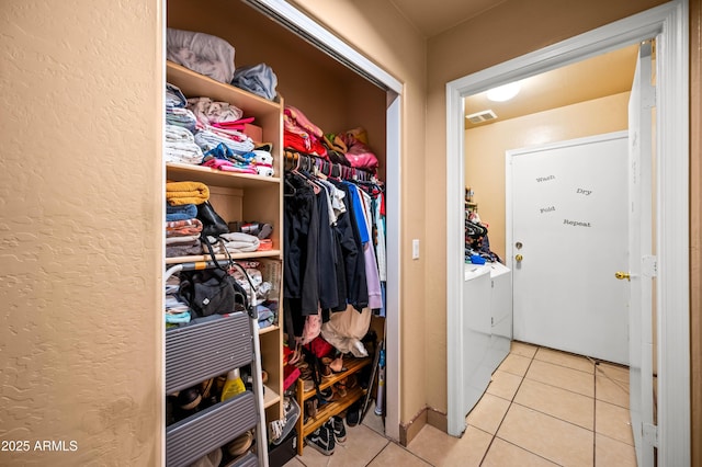 interior space with laundry area, separate washer and dryer, visible vents, and tile patterned floors