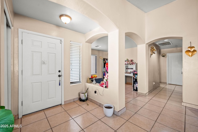 foyer entrance featuring light tile patterned floors, visible vents, and baseboards