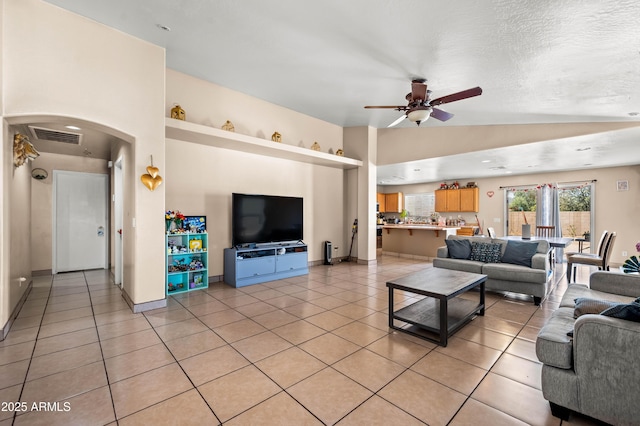 living room with light tile patterned floors, vaulted ceiling, arched walkways, and visible vents