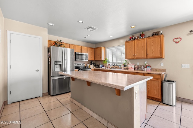 kitchen with visible vents, appliances with stainless steel finishes, a center island, light countertops, and a sink