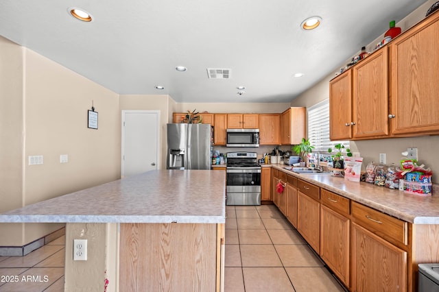 kitchen featuring light tile patterned floors, visible vents, a center island, stainless steel appliances, and a sink