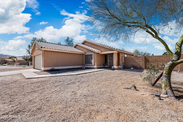 view of front of home with driveway, a tile roof, fence, and stucco siding