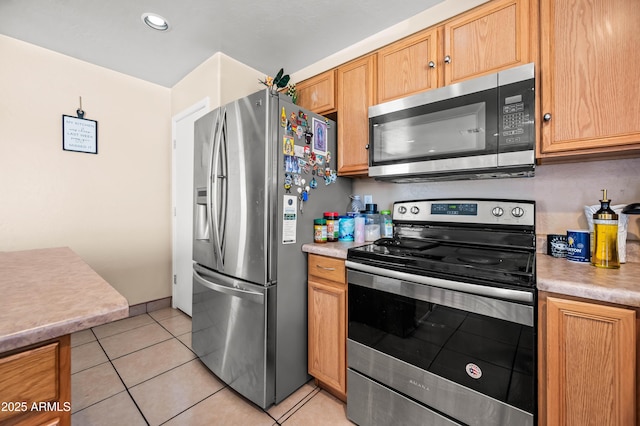 kitchen featuring light tile patterned floors, baseboards, appliances with stainless steel finishes, and light countertops