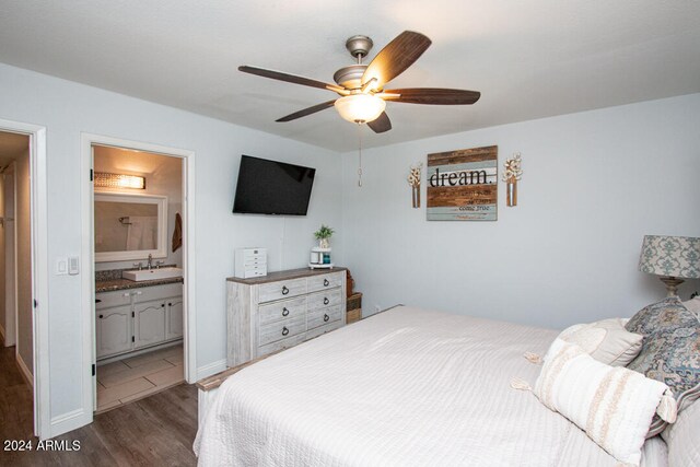 bedroom with ensuite bath, sink, dark hardwood / wood-style floors, and ceiling fan