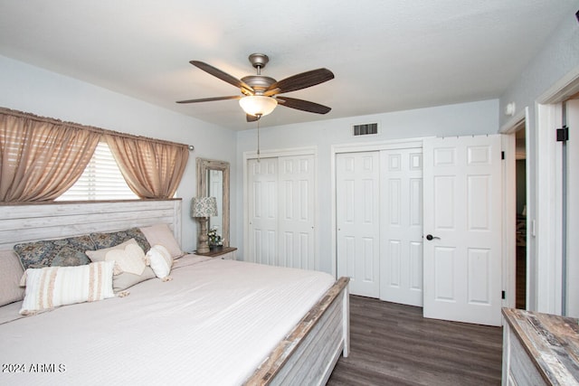 bedroom with ceiling fan, multiple closets, and dark hardwood / wood-style flooring