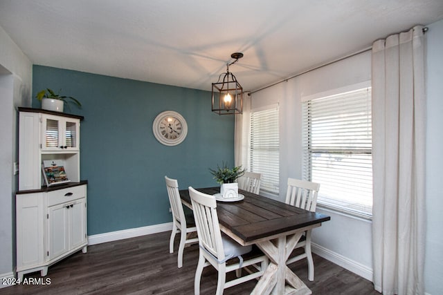 dining room with dark wood-type flooring and an inviting chandelier