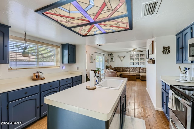 kitchen with light hardwood / wood-style floors, sink, an island with sink, and blue cabinets