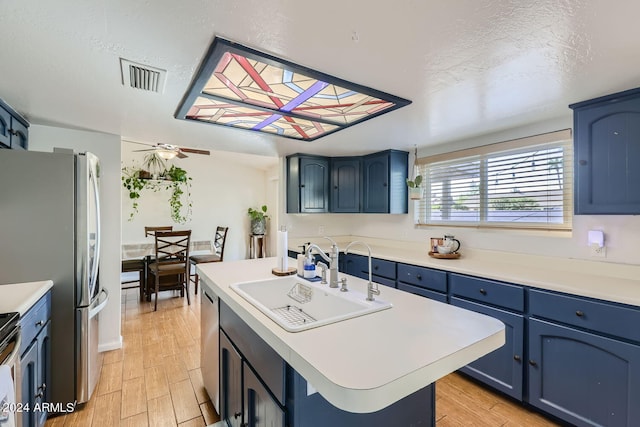 kitchen featuring a kitchen island, light hardwood / wood-style flooring, sink, blue cabinets, and appliances with stainless steel finishes