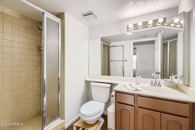 bathroom featuring vanity, a textured ceiling, toilet, and an enclosed shower