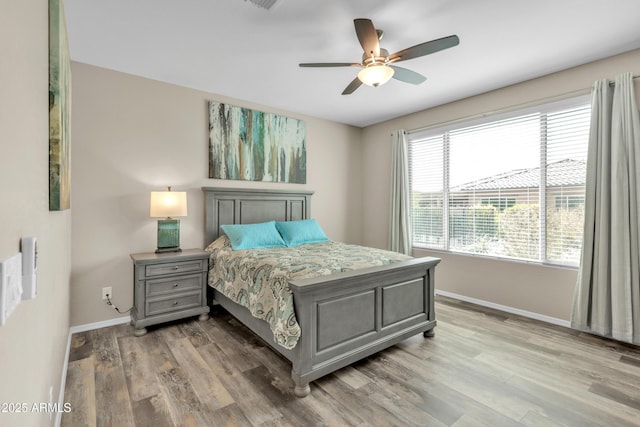 bedroom featuring light wood finished floors, baseboards, visible vents, and ceiling fan