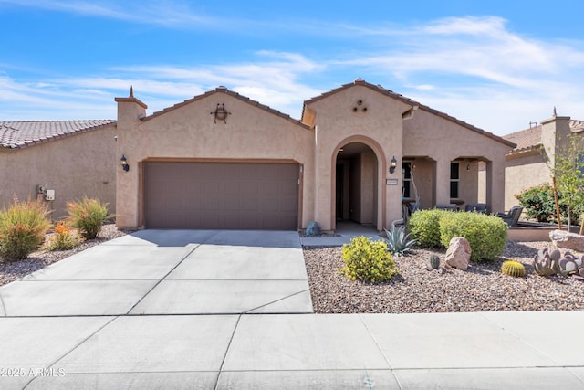 mediterranean / spanish home featuring a tile roof, a garage, driveway, and stucco siding