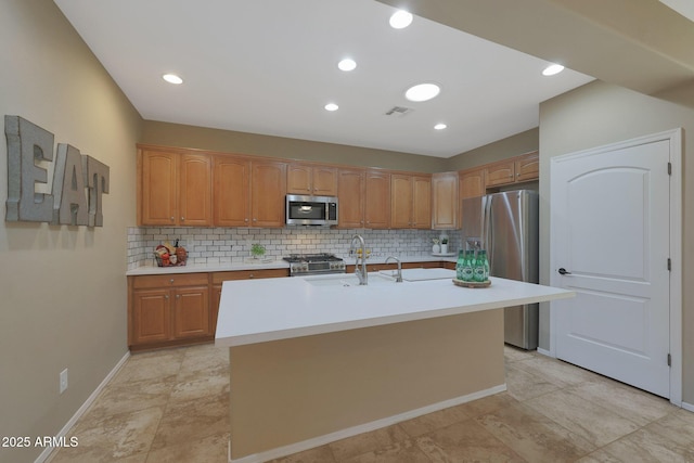 kitchen featuring stainless steel appliances, decorative backsplash, a center island with sink, and sink