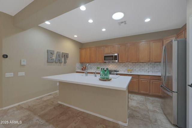 kitchen with appliances with stainless steel finishes, an island with sink, sink, backsplash, and light tile patterned floors