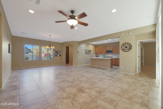 unfurnished living room featuring ceiling fan with notable chandelier