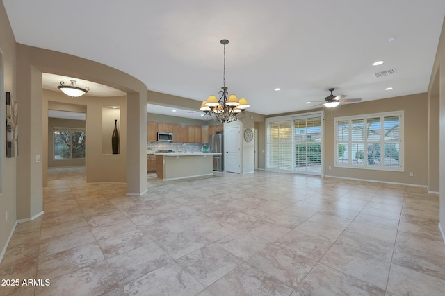 unfurnished living room featuring ceiling fan with notable chandelier