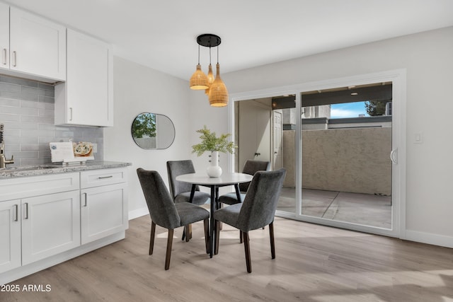 dining space featuring light wood-style flooring and baseboards