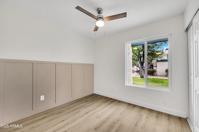 spare room featuring light wood-type flooring, ceiling fan, and baseboards