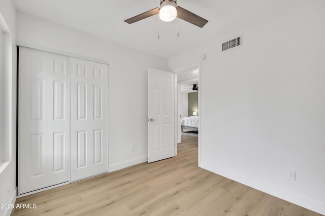 unfurnished bedroom with baseboards, visible vents, ceiling fan, light wood-style floors, and a closet