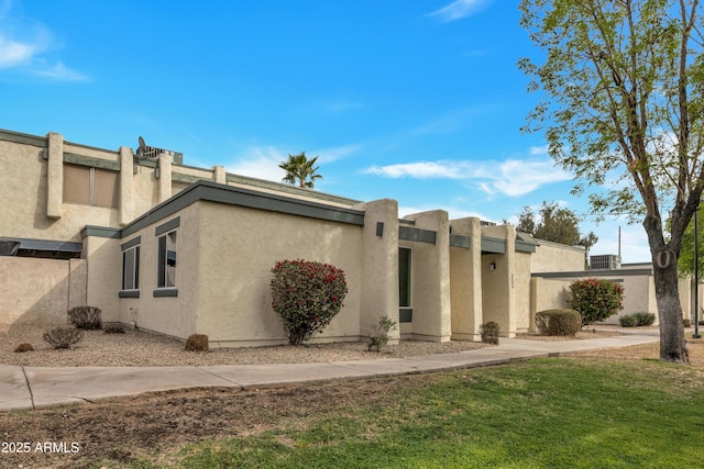 view of side of property featuring a lawn and stucco siding