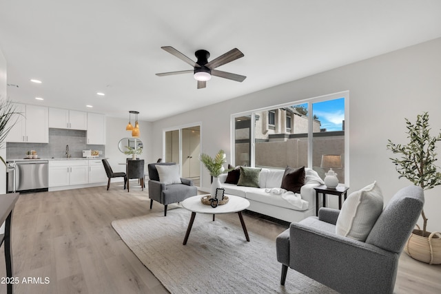 living room featuring light wood-style floors, a ceiling fan, and recessed lighting