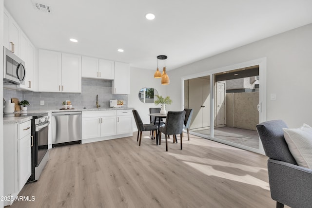 kitchen featuring appliances with stainless steel finishes, light countertops, visible vents, and white cabinetry