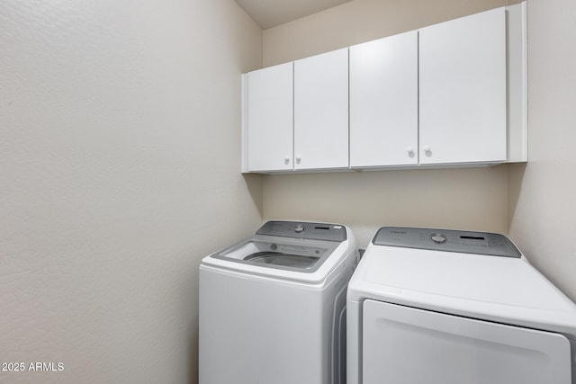 clothes washing area featuring independent washer and dryer and cabinet space