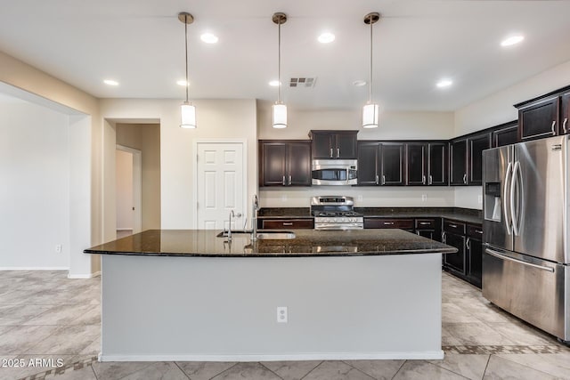 kitchen featuring stainless steel appliances, a sink, visible vents, dark stone counters, and an island with sink