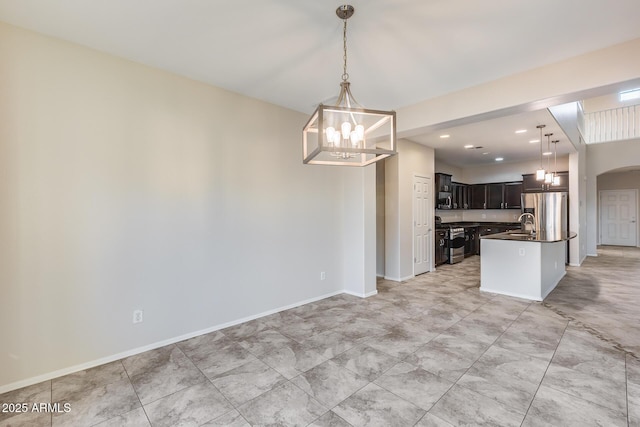 kitchen featuring dark brown cabinetry, decorative light fixtures, a chandelier, stainless steel appliances, and a kitchen island with sink