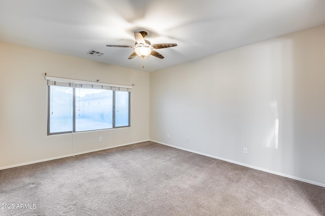 carpeted spare room with baseboards, visible vents, and a ceiling fan